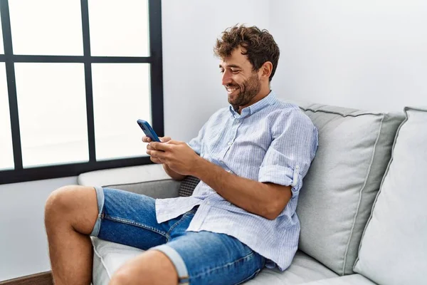 Genç Spanyol Adam Akıllı Telefon Kullanıyor Evdeki Kanepede Oturuyor — Stok fotoğraf