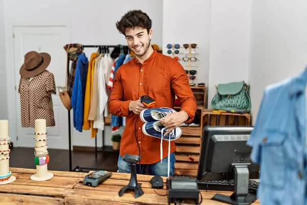 Young hispanic shopkeeper man smiling happy working at clothing store.