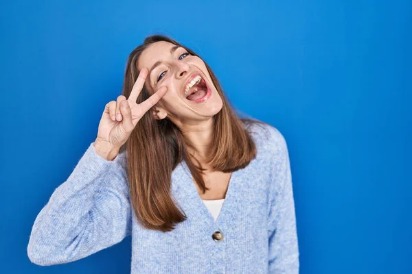 Young Woman Standing Blue Background Doing Peace Symbol Fingers Face — Stockfoto