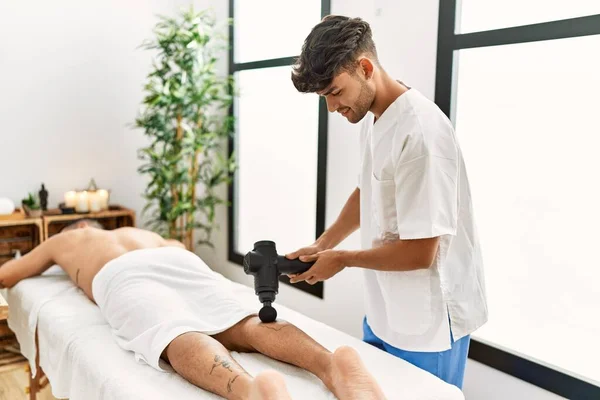 Due Uomini Ispanici Fisioterapista Paziente Massaggiare Gambe Utilizzando Pistola Percussione — Foto Stock