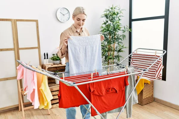 Joven Mujer Caucásica Sonriendo Confiado Colgando Ropa Sala Lavandería —  Fotos de Stock