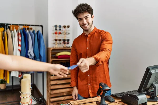 Young Hispanic Shopkeeper Man Giving Credit Card Customer Clothing Store — Stockfoto