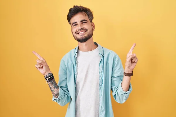 Молодий Іспаномовний Чоловік Татуюваннями Стоїть Над Жовтим Тлом Посміхаючись Впевнено — стокове фото