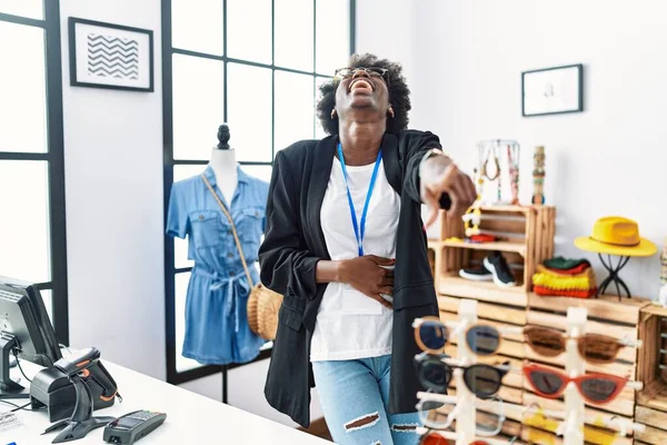 African young woman working as manager at retail boutique laughing at you, pointing finger to the camera with hand over body, shame expression