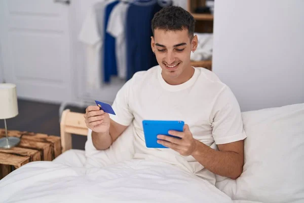 Junger Hispanischer Mann Sitzt Mit Touchpad Und Kreditkarte Auf Bett — Stockfoto