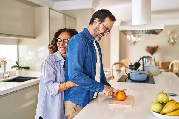 Pareja Hispana Mediana Edad Abrazándose Mutuamente Cortando Naranja Cocina —  Fotos de Stock