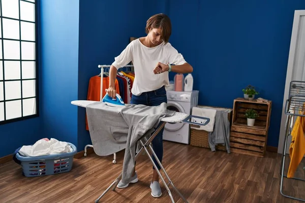 Young Beautiful Hispanic Woman Ironing Clothes Looking Watch Laundry Room — ストック写真