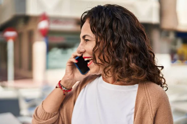 Orta yaşlı İspanyol kadın dışarıda telefonla konuşuyor.