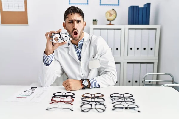 Young Optician Man Holding Optometry Glasses Shock Face Looking Skeptical — 图库照片