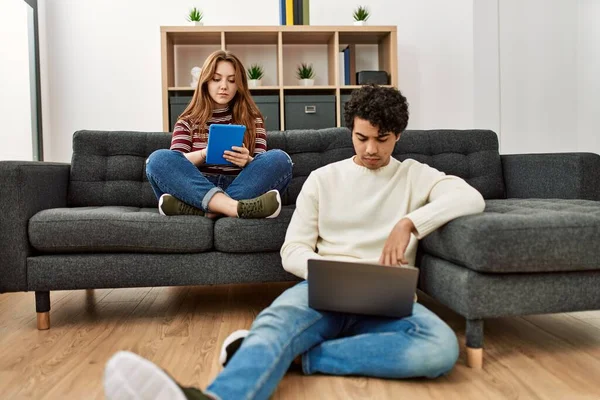 一对年轻夫妇 表情严肃 坐在沙发上 用笔记本电脑和触摸板 — 图库照片
