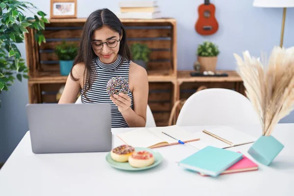 Young Hispanic Girl Eating Doughnut Studying Home — Stockfoto