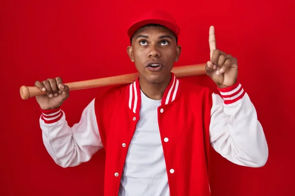 Young Hispanic Man Playing Baseball Holding Bat Amazed Surprised Looking —  Fotos de Stock