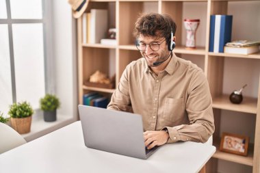 Çağrı merkezi kulaklığı takan İspanyol genç adam pozitif ve mutlu görünüyor ve kendine güvenen bir gülümsemeyle dişlerini gösteriyor. 