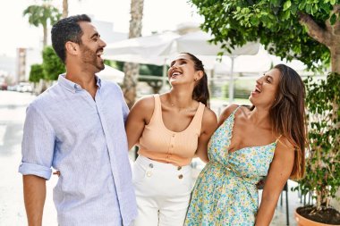 Üç İspanyol arkadaş şehirde mutlu bir şekilde gülüyor ve sarılıyorlar..