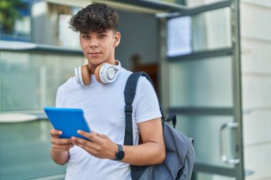 Latin kökenli genç bir öğrenci üniversitede rahat bir ifadeyle dokunmatik ped kullanıyor.