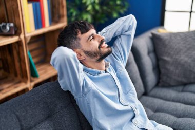 Genç İspanyol adam, ellerini başının üstüne koyup evinde kanepede oturarak rahatladı.