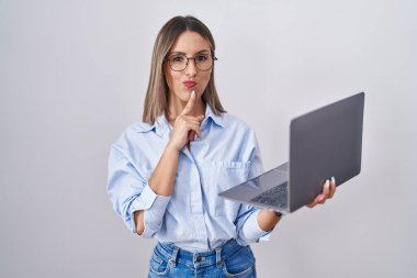Young woman working using computer laptop thinking concentrated about doubt with finger on chin and looking up wondering 