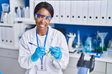 Young african american woman scientist smiling confident writing on test tube at laboratory