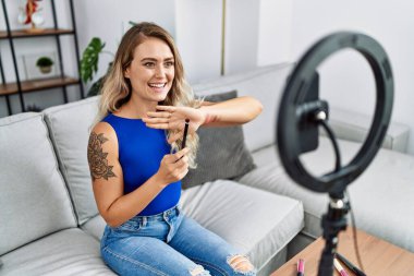 Evde akıllı telefondan makyaj dersi alan genç bir kadın.