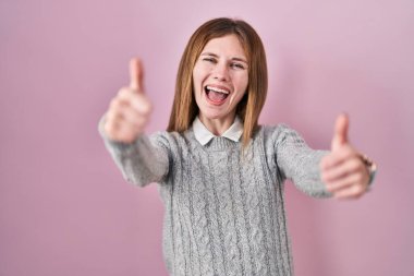 Pembe arka planda duran güzel bir kadın elleriyle olumlu jest yapmayı onaylıyor. Gülümsüyor ve başarı için mutlu. kazanan jest. 