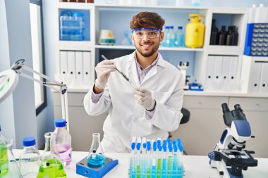 Young arab man scientist analysing plant test tube at laboratory