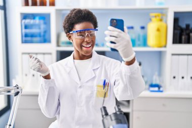 Afrika kökenli Amerikalı bir kadın bilim adamının laboratuarında çalışıyor. Akıllı telefonuyla video görüşmesi yapıyor. Gururla bağırıyor, zaferi kutluyor ve kollarını kaldırarak başarıyı kutluyor. 