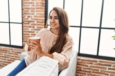 Genç İspanyol kadın gülerek evde kahve içiyor.