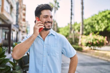 Genç İspanyol adam gülümsüyor. Şehirdeki akıllı telefondan konuşuyor..