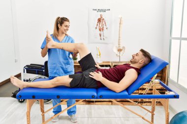 Genç İspanyol fizyoterapist kadın klinikteki adama bacak rehabilitasyonu yapıyor..