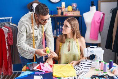Man and woman tailors holding cloth and thread at clothing factory