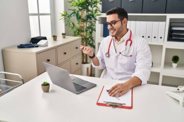 Sakallı genç İspanyol doktor klinikte online randevu veriyor. Gururla bağırıyor, zaferi ve başarıyı kutluyor. 