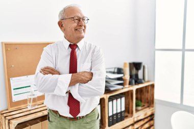 Üst düzey bir iş adamı, kollarını kavuşturup ofiste el kol geziyor.