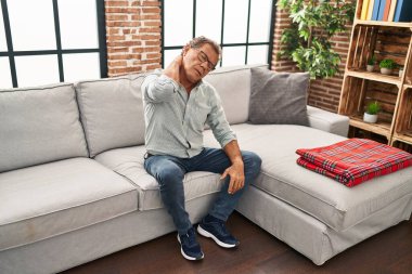 Middle age man touching neck suffering for pain at home