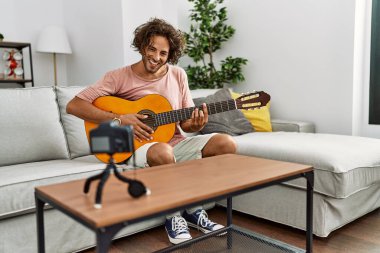 Evde klasik gitar çalan Latin asıllı genç bir adam kayıt yapıyor..