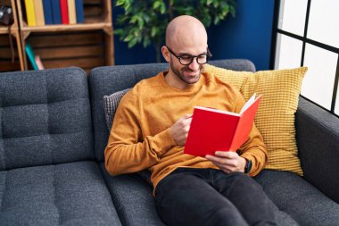 Genç adam kitap okuyor ve evde kahve içiyor.