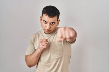 Young arab man wearing casual t shirt punching fist to fight, aggressive and angry attack, threat and violence 