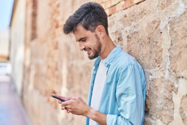 Sokakta akıllı telefon kullanan, kendine güvenen genç bir İspanyol.
