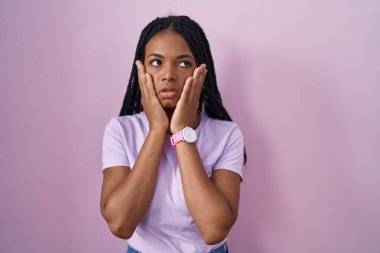 African american woman with braids standing over pink background tired hands covering face, depression and sadness, upset and irritated for problem 