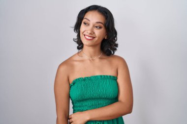 Tecrit edilmiş arka planda duran genç İspanyol kadın yüzünde gülümseme, doğal bir ifade ile yan yana bakıyor. Kendinden emin gülen. 