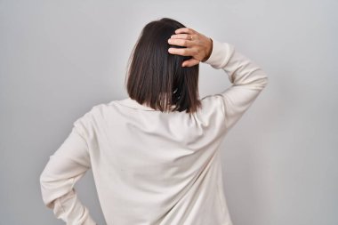 Orta yaşlı İspanyol kadın izole edilmiş arka planda dikiliyor. Elleri başının üstünde şüpheyi düşünüyor. 