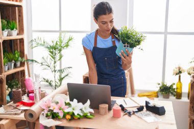Çiçekçide dizüstü bilgisayar kullanan güzel İspanyol bir çiçekçi kadın.