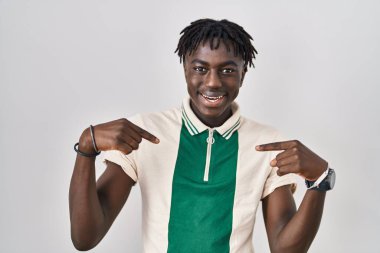 Afrikalı bir adam izole edilmiş arka planda duruyor. Yüzünde bir gülümsemeyle, kendini gururlu ve mutlu olarak gösteriyor.. 