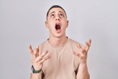 İzole edilmiş arka planda duran genç adam kızgın ve çılgın bir şekilde bağırıyor ve agresif bir ifade ve kollarla bağırıyor. hüsran kavramı. 