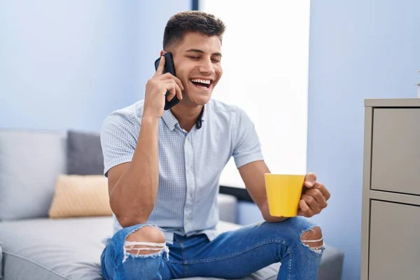 Hombre Hispano Joven Bebiendo Café Hablando Teléfono Inteligente Casa —  Fotos de Stock