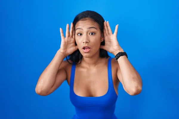 Hispanic Woman Standing Blue Background Trying Hear Both Hands Ear — Stok fotoğraf
