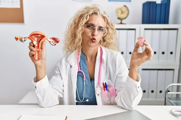 Middle Age Doctor Woman Holding Menstrual Cup Looking Camera Blowing — Stock Photo, Image