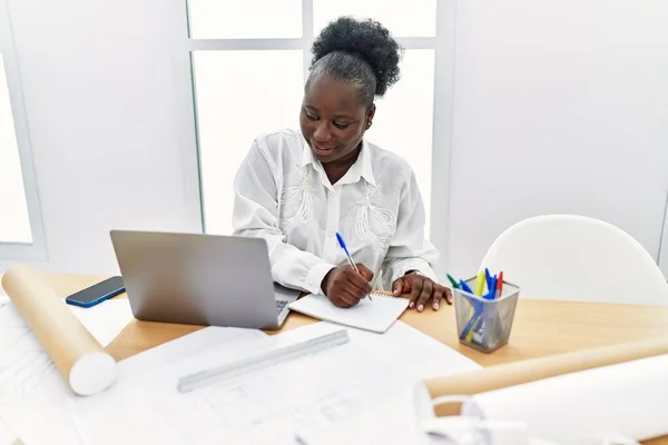 アフリカ系アメリカ人の若い女性建築家がノートパソコンでノートを書く — ストック写真