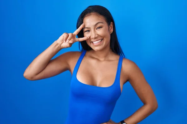 Hispanic Woman Standing Blue Background Doing Peace Symbol Fingers Face — Foto de Stock