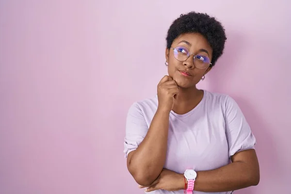 Mujer Afroamericana Joven Pie Sobre Fondo Rosa Con Mano Barbilla —  Fotos de Stock