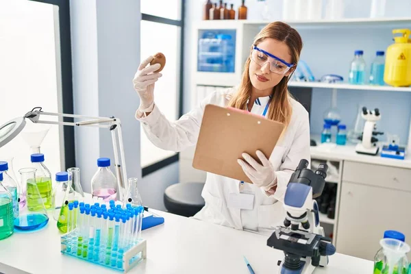 Young Blonde Woman Wearing Scientist Uniform Holding Kiwi Clipboard Laboratory — Fotografia de Stock